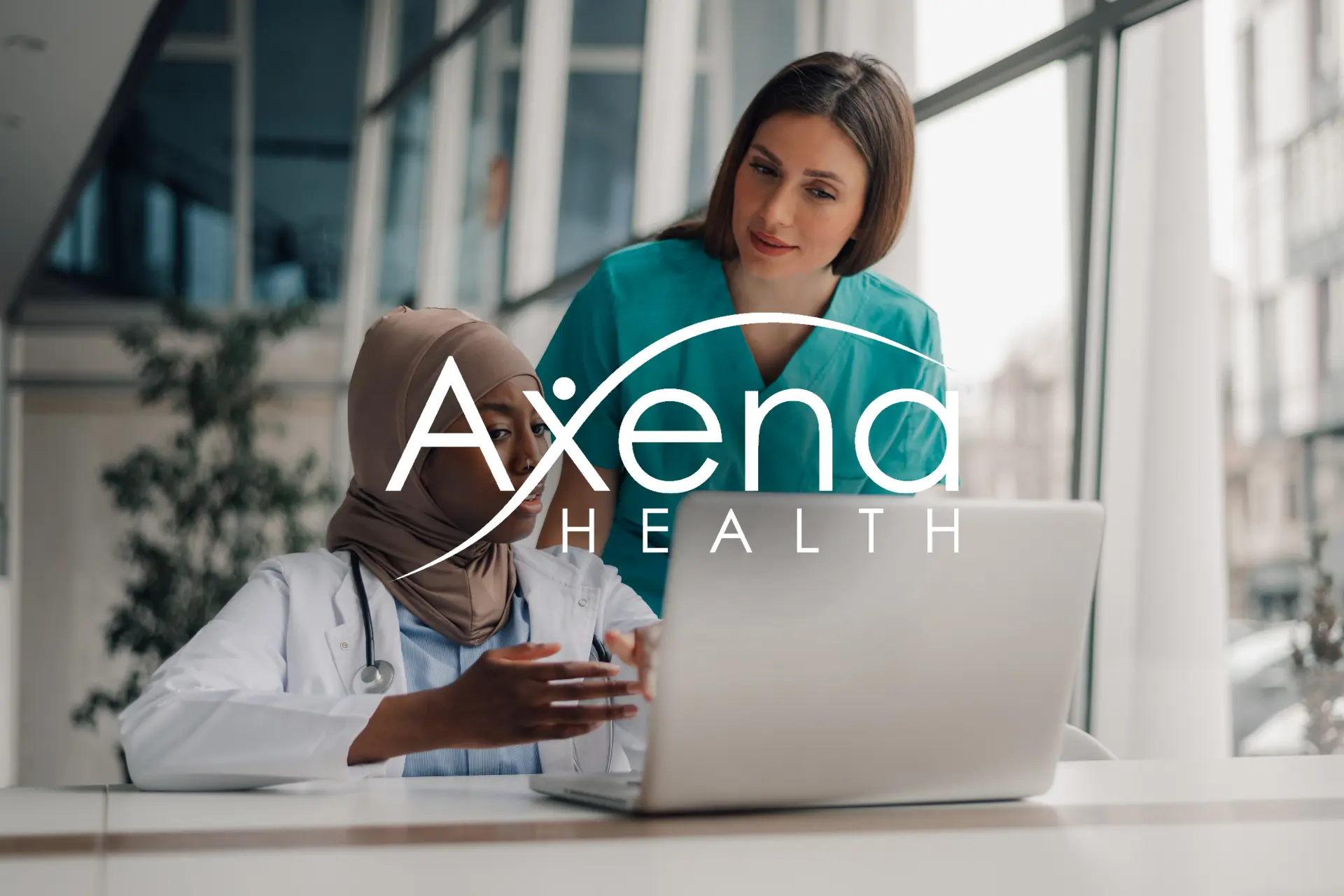 Two Axena Health clinicians reviewing a laptop together, with the Axena Health logo